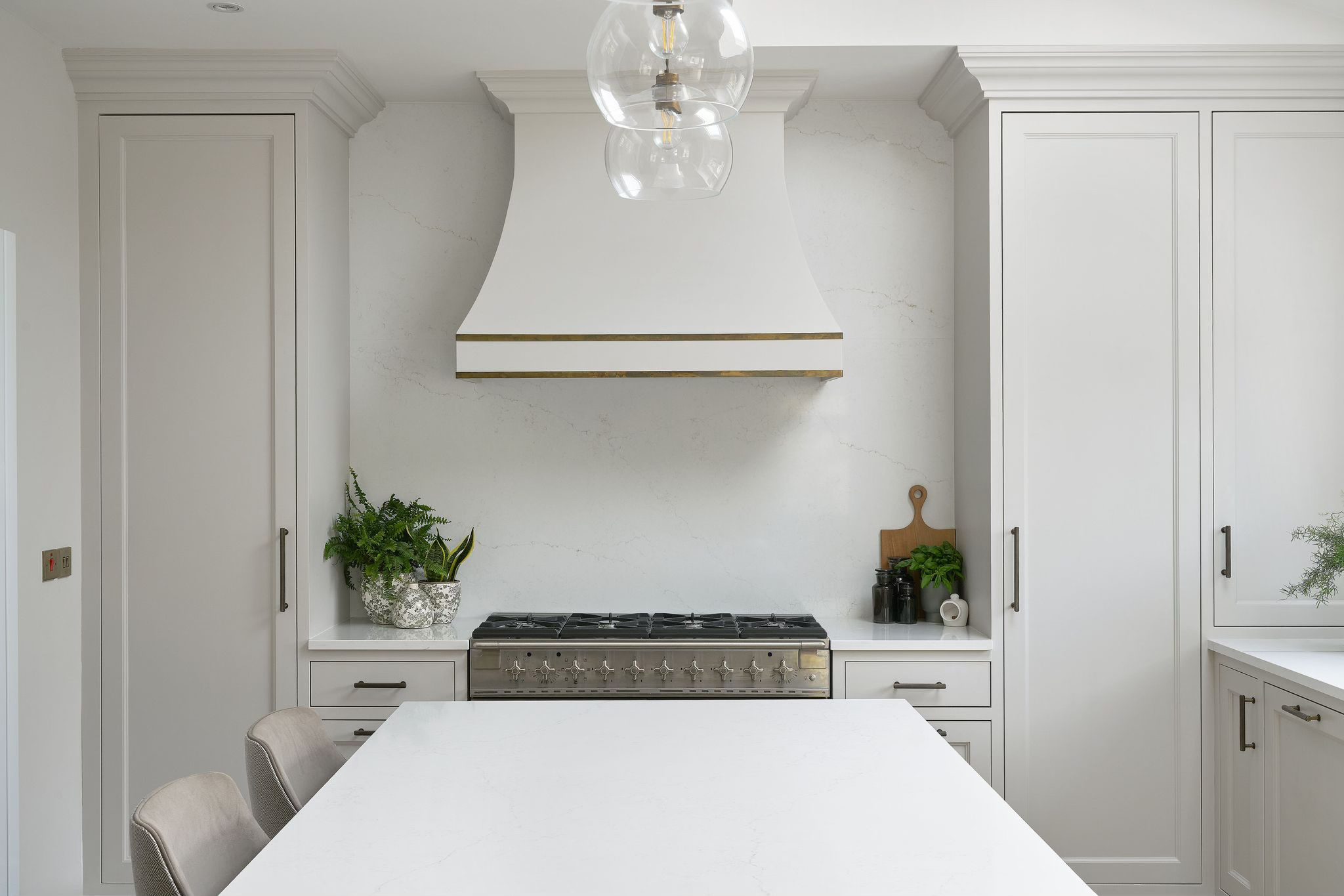 White shaker kitchen with an arched range hood, marble splashback and brass trim in Blackrock, Dublin