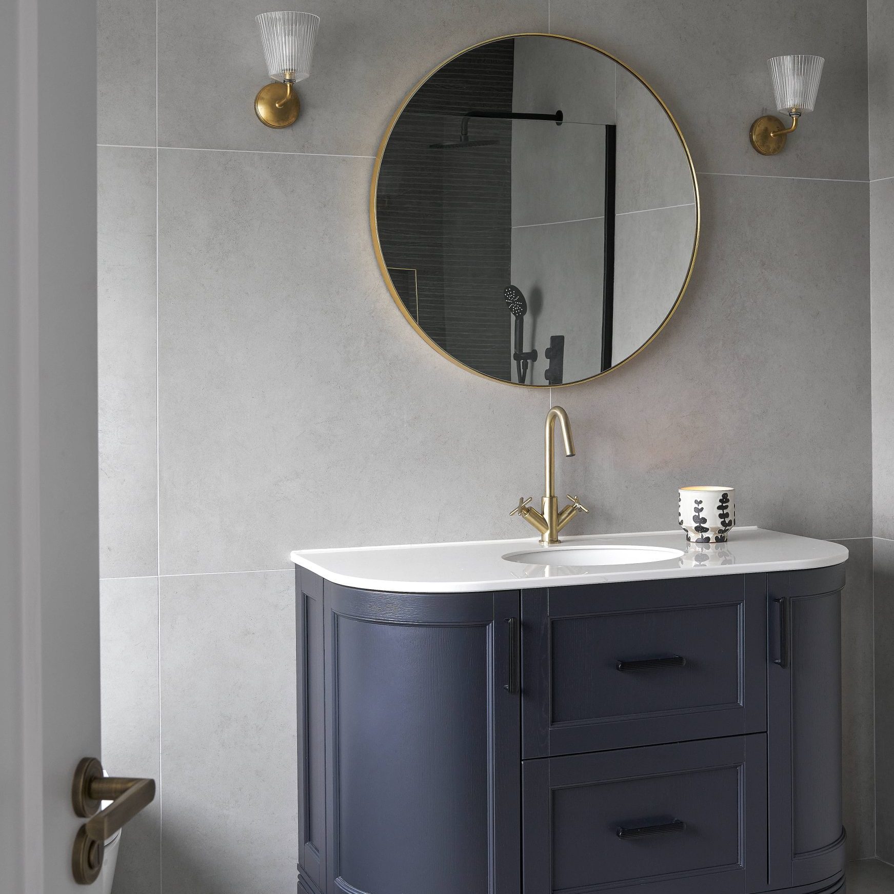 Mount Alton bathroom vanity with round mirror, gold fixtures, and blue cabinet.