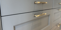 Rectangle 1 (16) Close-up of modern gray drawers with gold handles beneath a white countertop, showcasing a sleek and contemporary cabinet design.