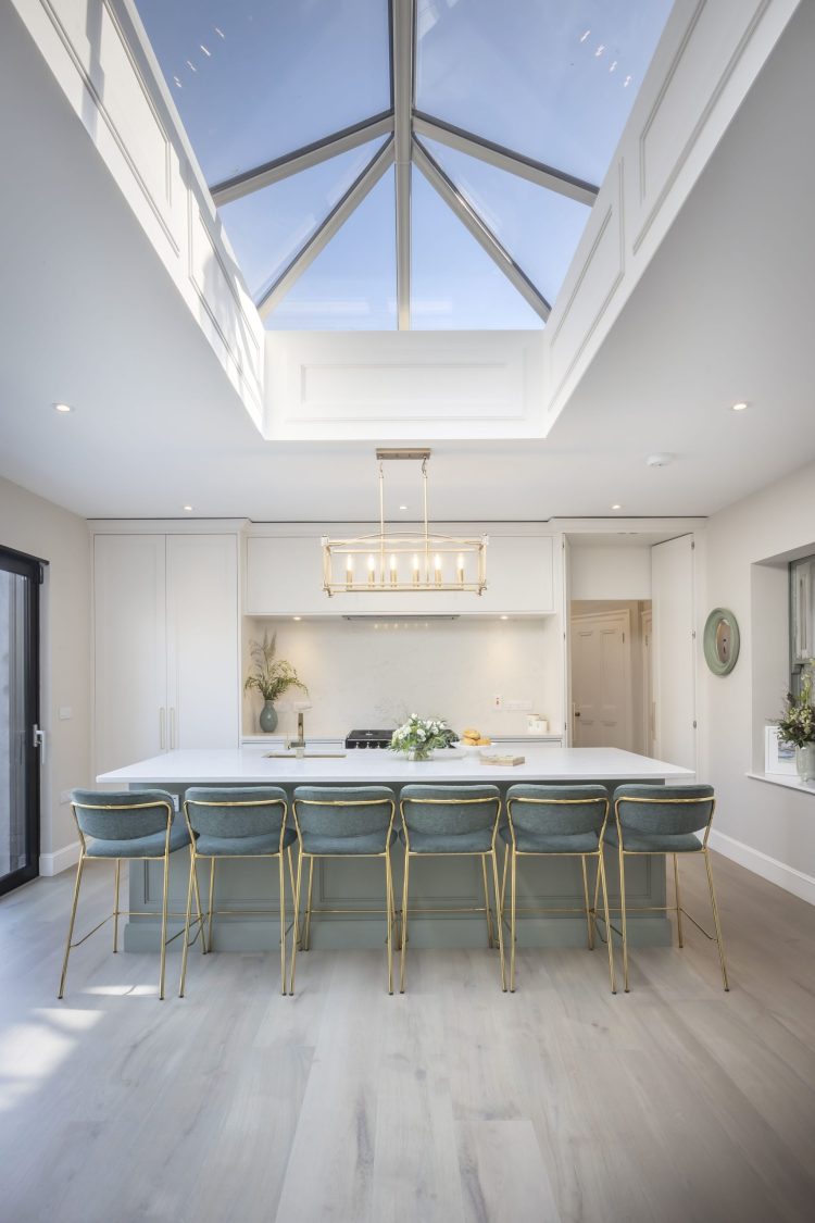 Large kitchen island, stone worktop gold & green chairs. Large Skylight