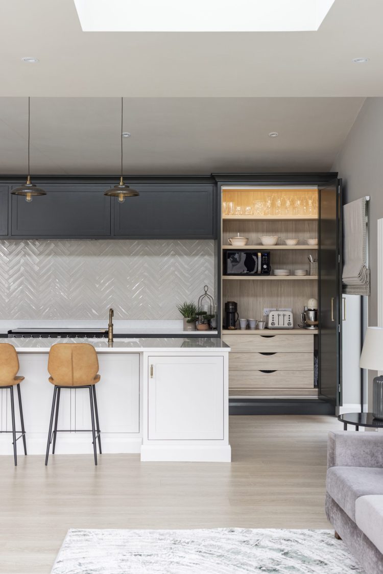 Laraghcon kitchen with dark cabinets, white island, and open pantry.