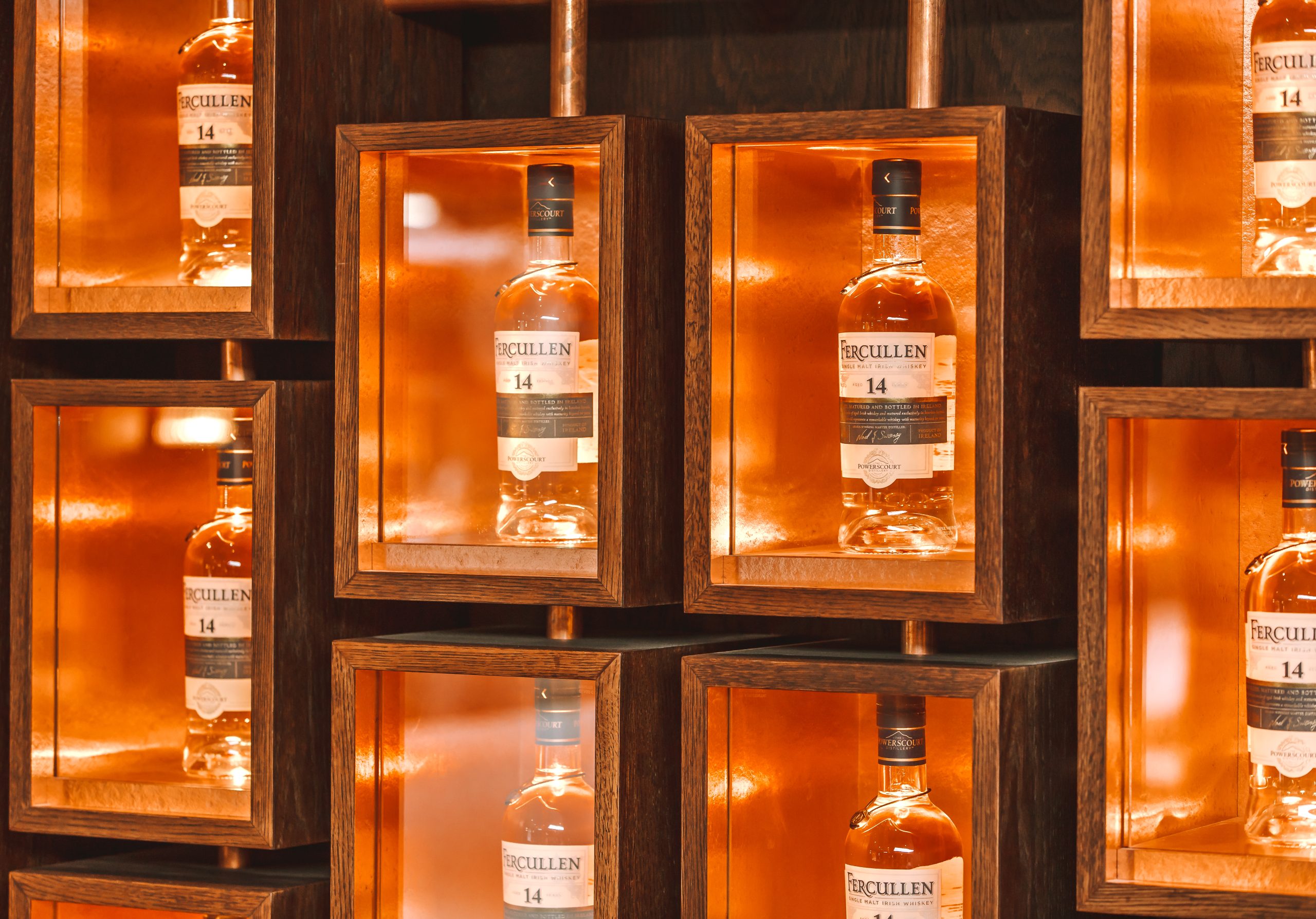 Powerscourt Distillery's Fercullen 14 single malt Irish whiskey bottles displayed in illuminated wooden frames.