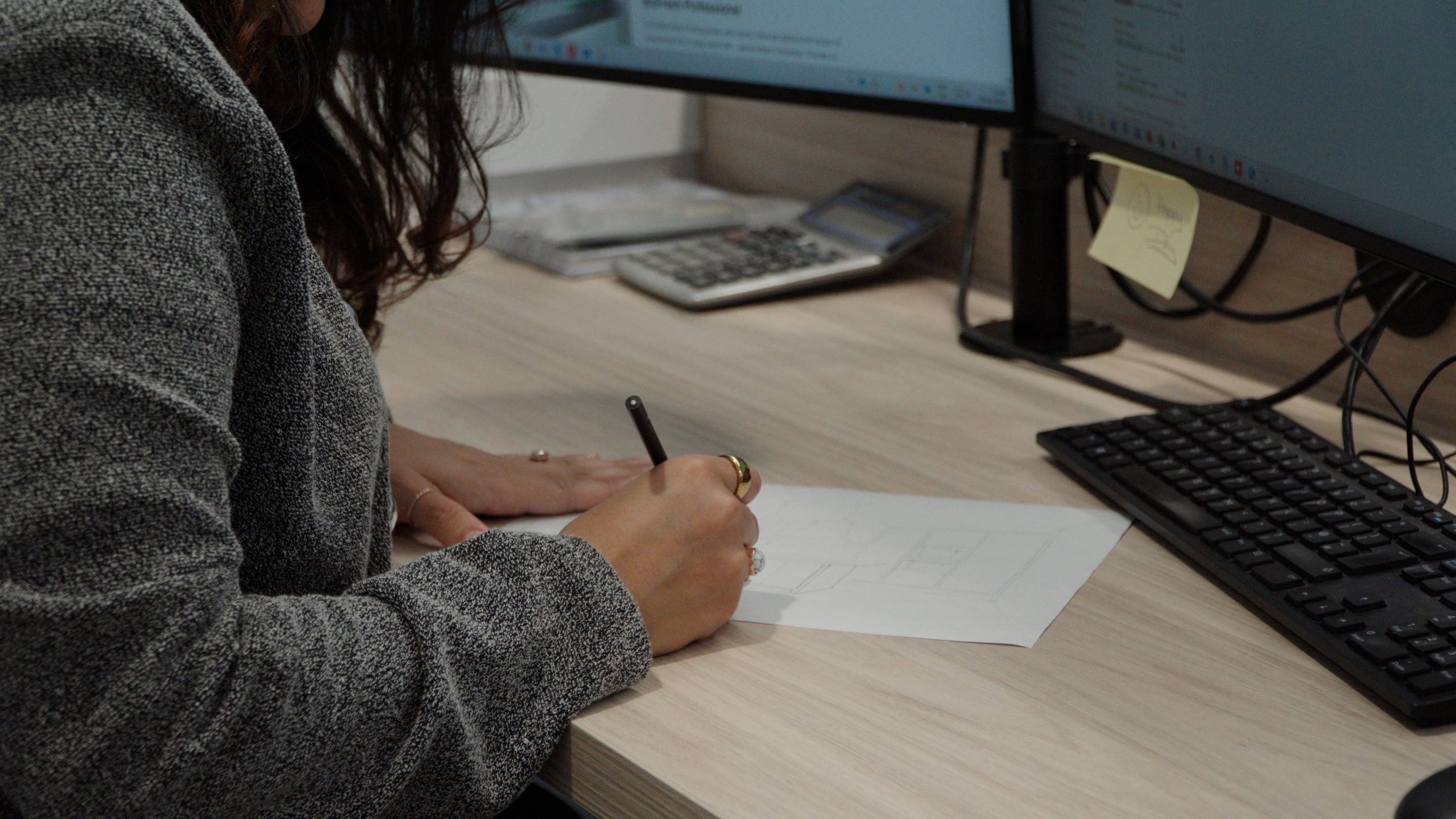 ONOVO designer drawing a floor plan at a desk with dual monitors during the design stage of a fit-out