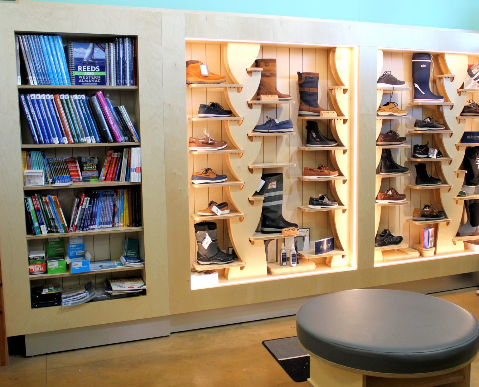 Birch plywood wall shelving with curved timber shoe displays and a bookcase of sailing titles in the Viking Marine store, Dun Laoghaire