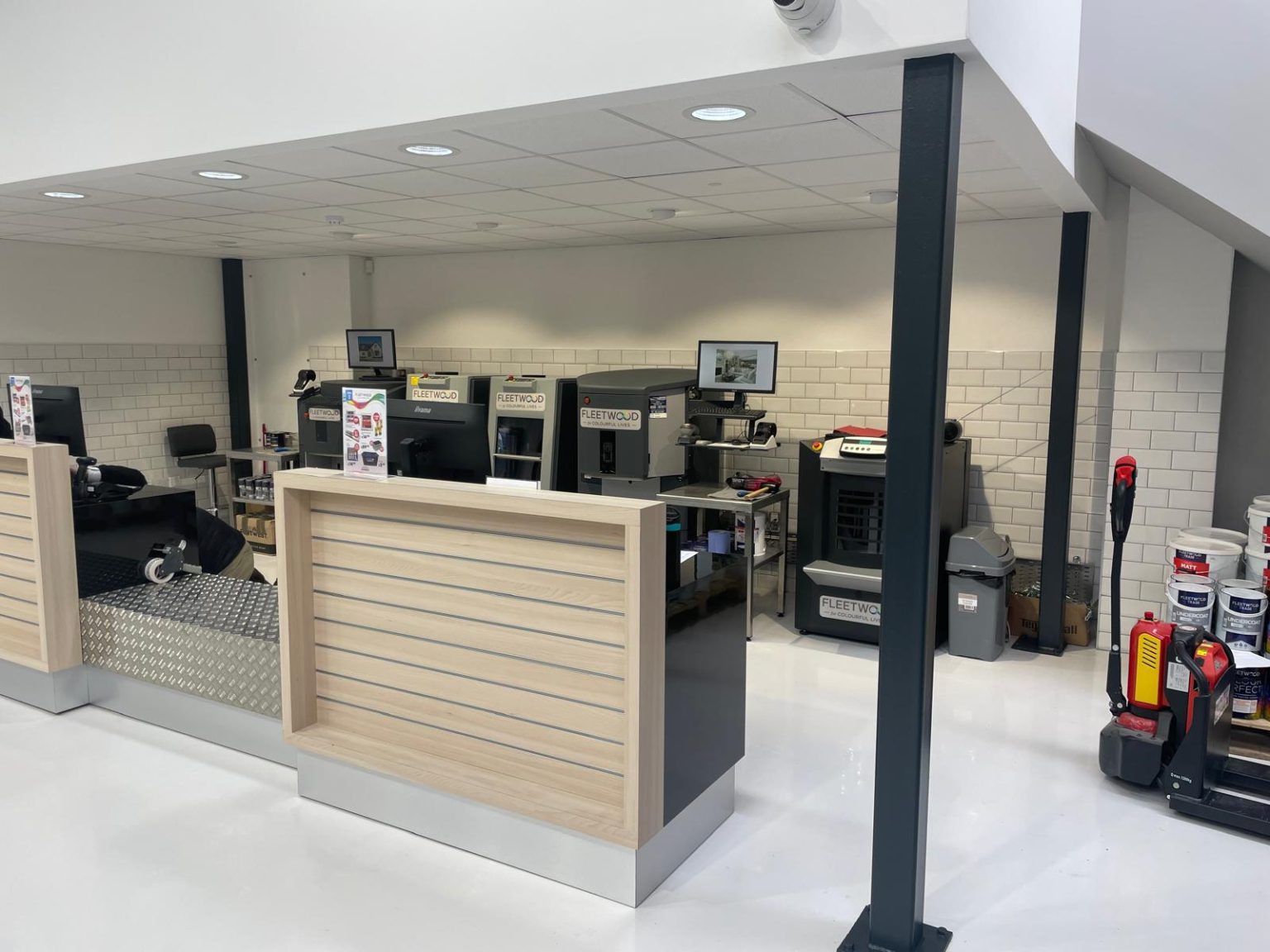 Service counter with a pale timber slatted front and a chequer-plate panel, with Fleetwood paint tinting machines behind, at the Fleetwood Paints decorating centre in Newbridge