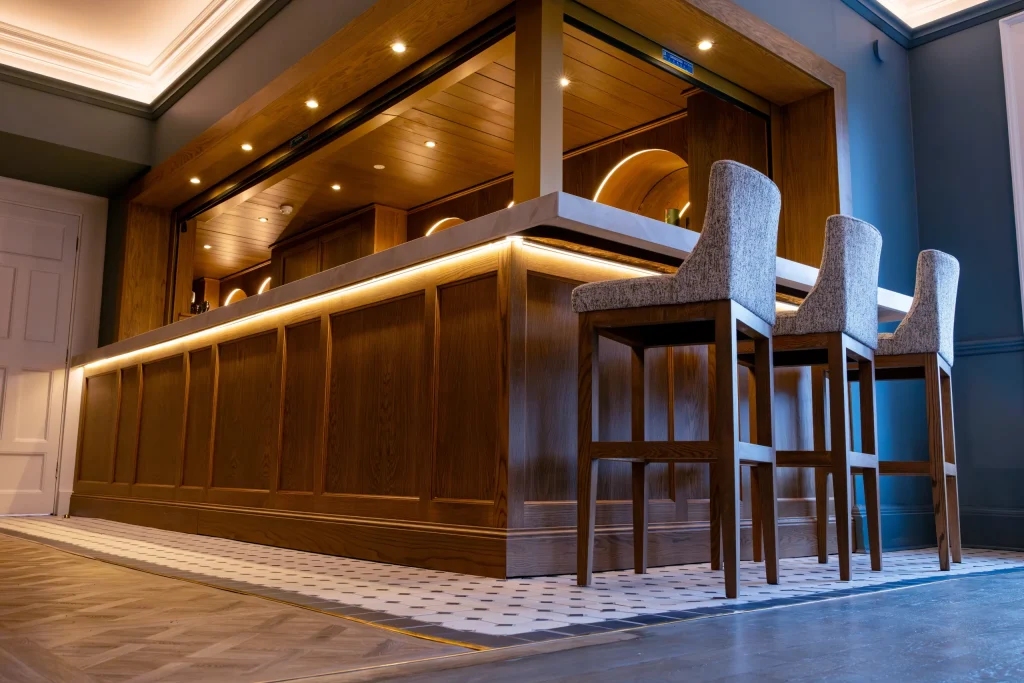 Oak bar counter with LED under-lighting and grey upholstered bar stools, Law Society Dublin
