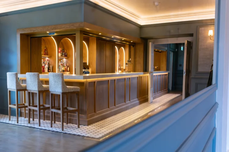 A luxury bar with three stools and ambient lighting